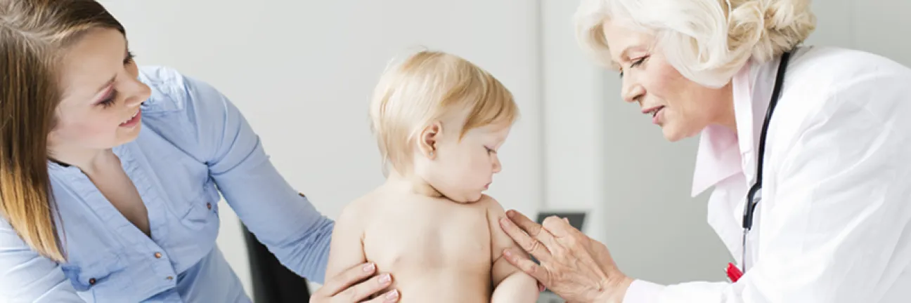 Doctor examines child who is being held by mother